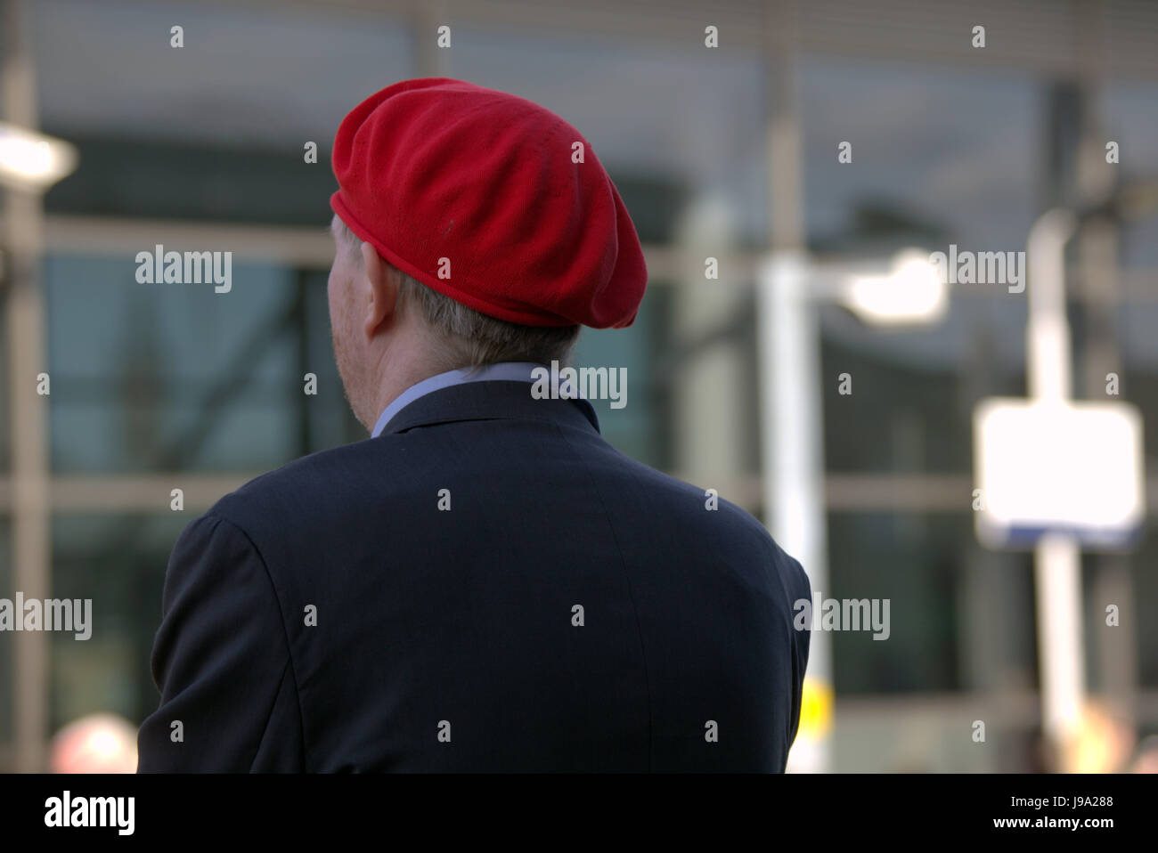 Uomo in una stazione ferroviaria in un berretto rosso sfondo bokeh di fondo al di fuori della messa a fuoco Foto Stock