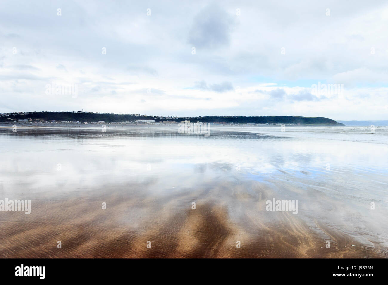 Condino, Devon, Inghilterra, Regno Unito, con la bassa marea, il cielo si riflette in un sottile strato di acqua sulla deserta spiaggia sabbiosa Foto Stock