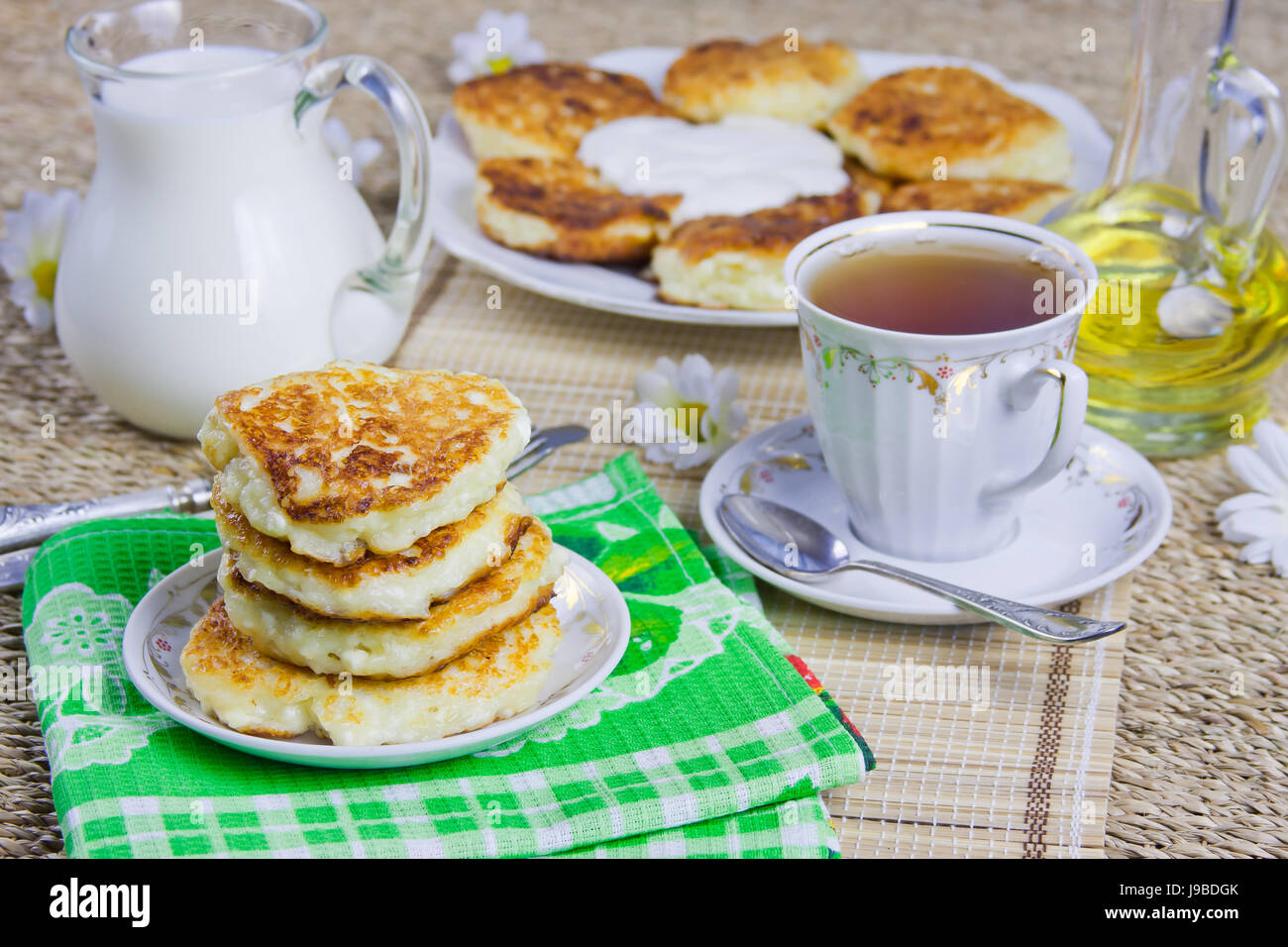 Tazza di tè, cagliata frittelle su un piatto da portata e latte Foto Stock