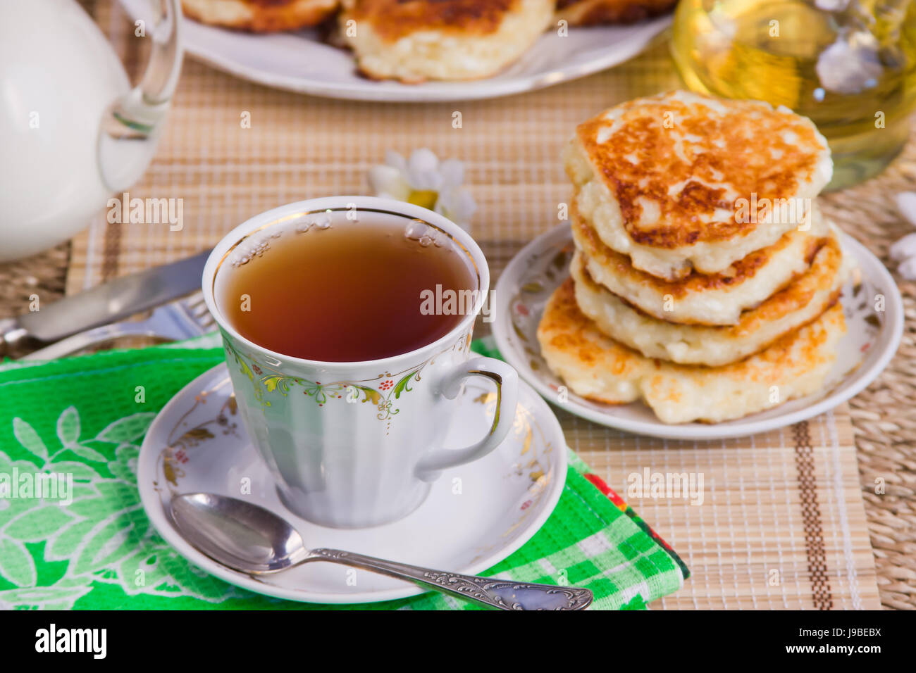 Tazza di tè, cagliata frittelle su un piatto da portata e latte Foto Stock