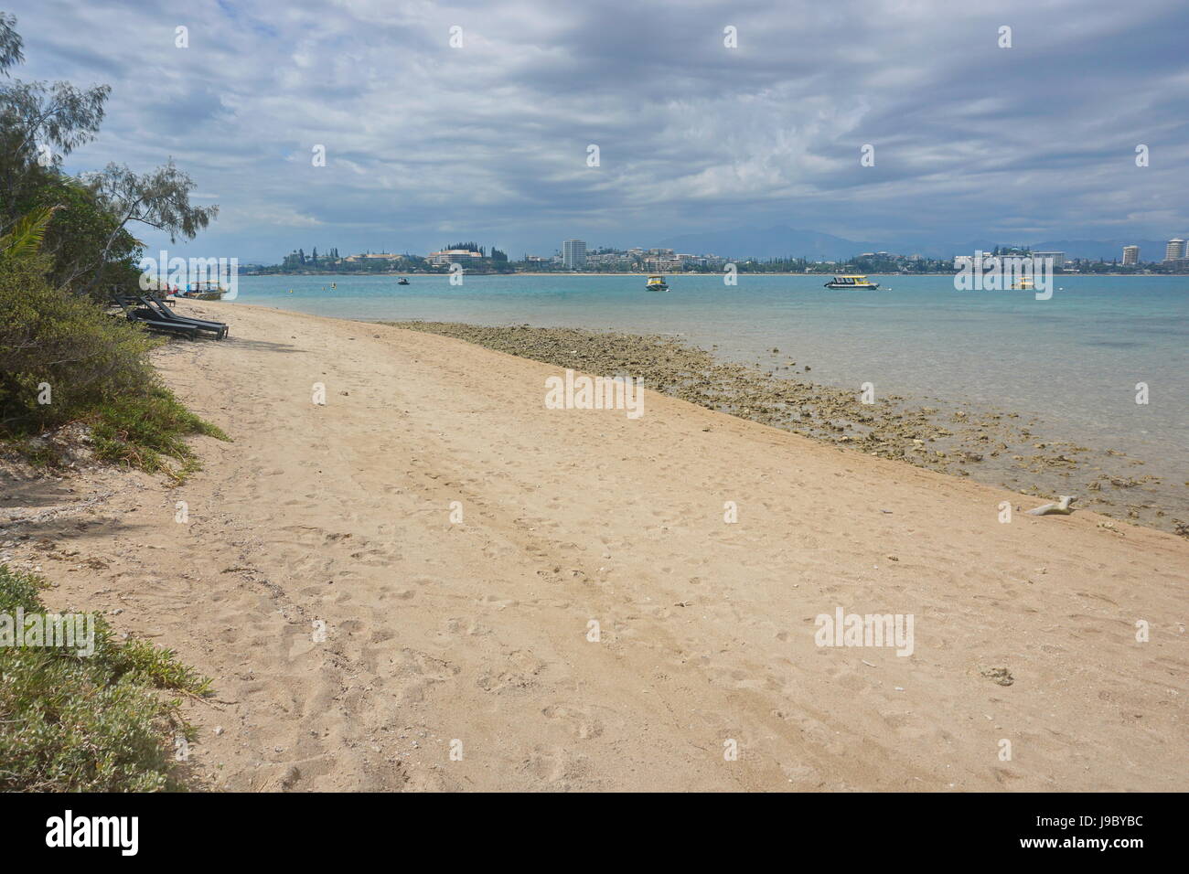 Spiaggia a riva dell'isolotto Canard e la fascia costiera di Anse Vata e la città di Noumea in background, Grande Terre isola, Nuova Caledonia, Oceania Foto Stock