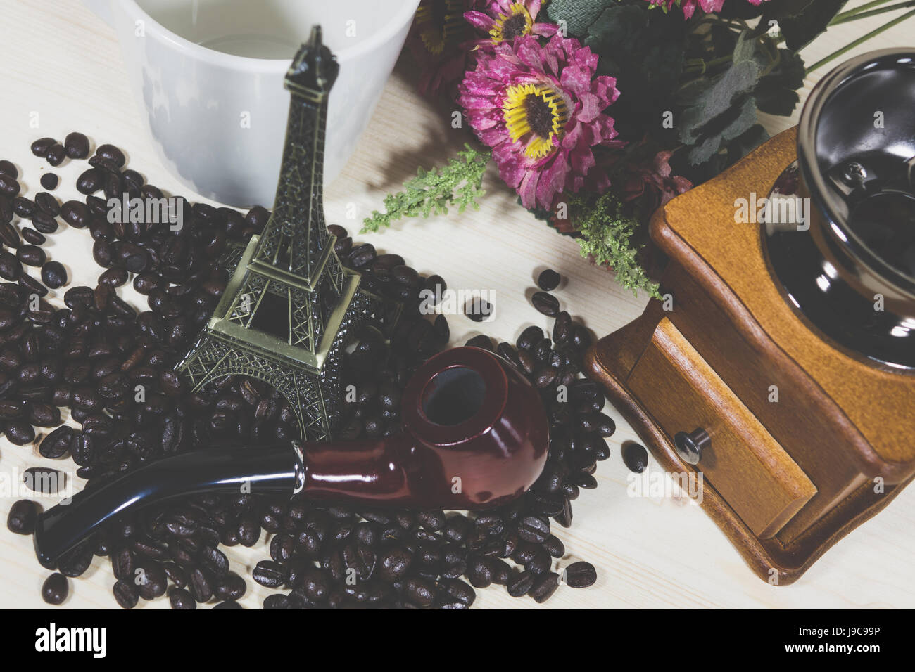 Tubo macinino da caffè chicco di caffè e la tazza di fiore su uno sfondo di legno Foto Stock