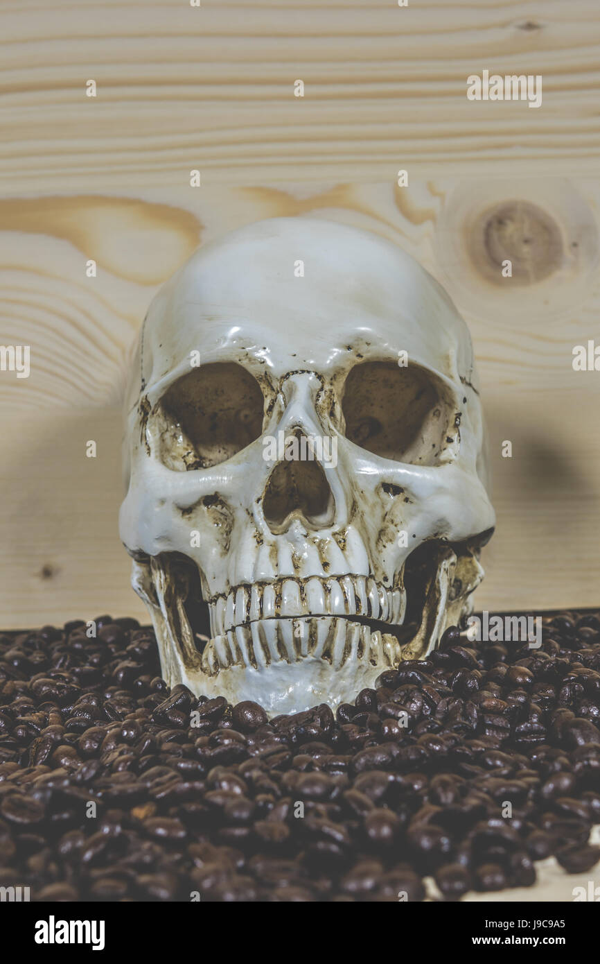 Il cranio con i chicchi di caffè su uno sfondo di legno Foto Stock