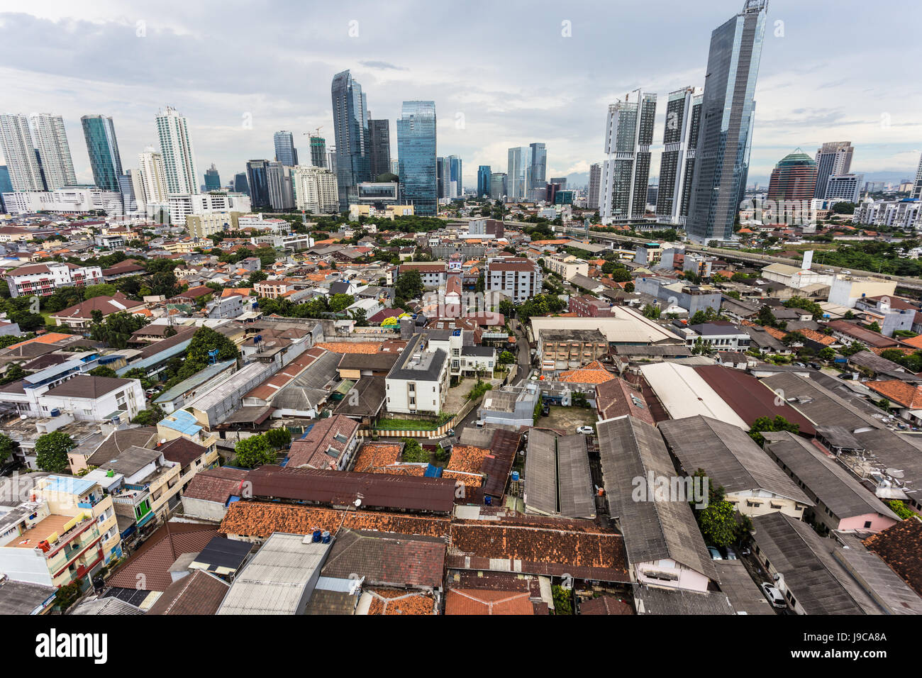 Bassi edifici residenziali di contrasti con gli alti e moderni edifici per uffici di Kuningan il quartiere degli affari di Jakarta, Indonesia città capitale. Foto Stock