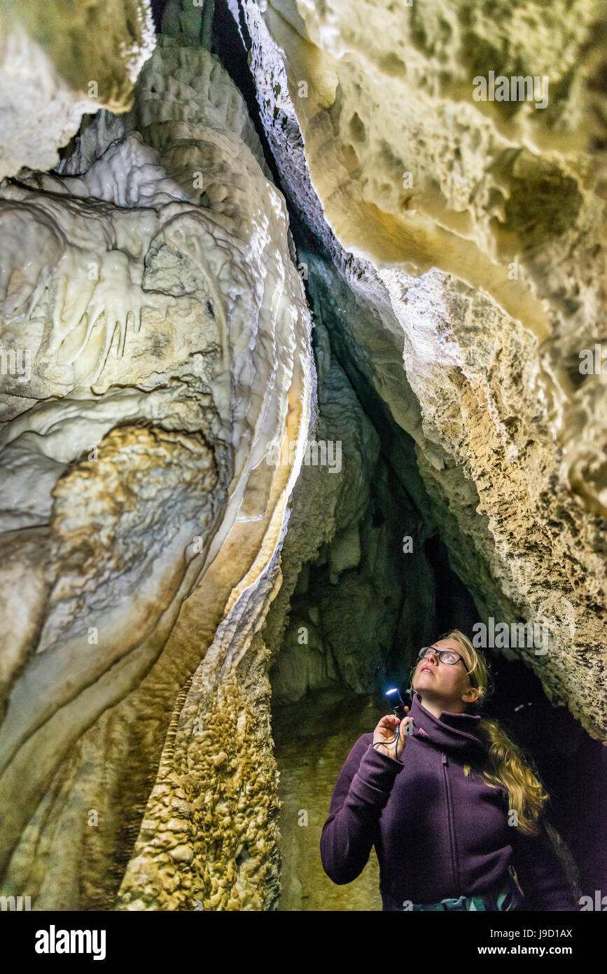Illuminazione donna una grotta con la torcia elettrica, grotte di calcare, Luxmore Grotta, Keplero via, Parco Nazionale di Fiordland, Isola del Sud Foto Stock