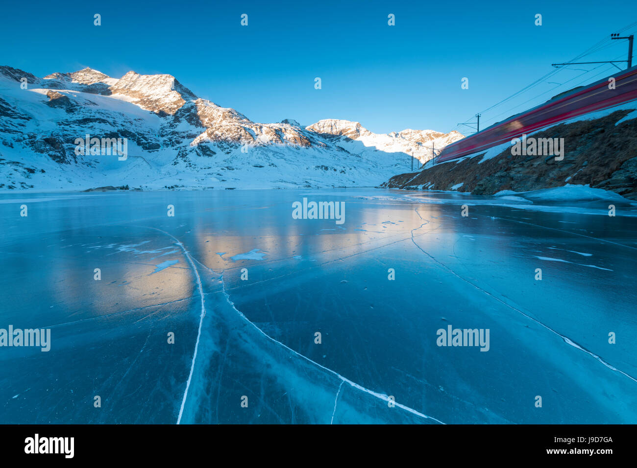 Il Bernina Express treno passa accanto al lago congelato Bianco, Passo Bernina del cantone dei Grigioni, Engadina, Svizzera, Europa Foto Stock