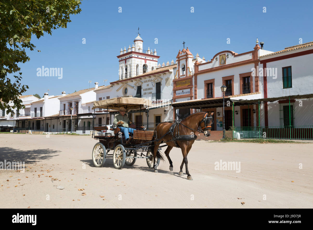 Cavallo e Carrozza a cavallo lungo le strade di sabbia con case di fraternità dietro, El Rocio, provincia di Huelva, Andalusia, Spagna, Europa Foto Stock