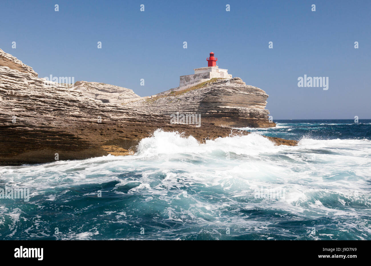 Onde del mare turchese schiantarsi sul granito bianche scogliere e del faro, Isole Lavezzi, Bonifacio, Corsica, Francia Foto Stock