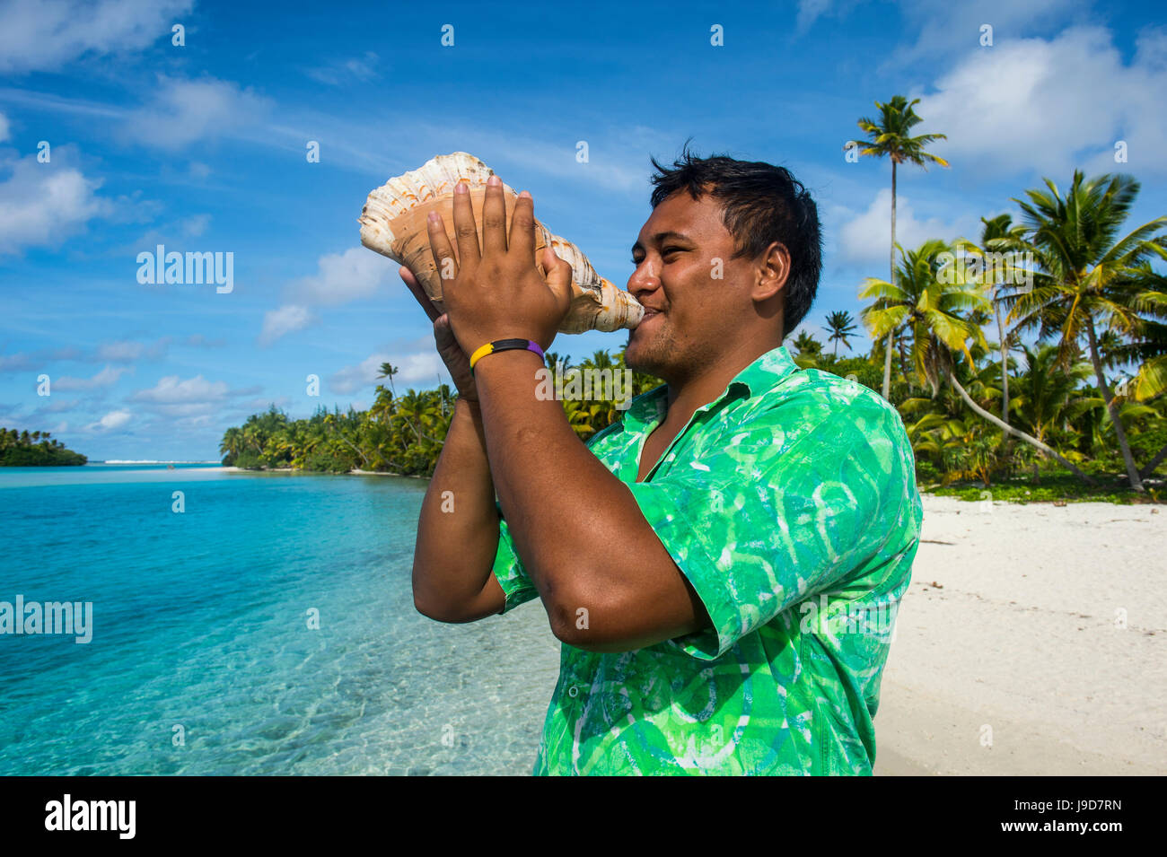 Uomo locale soffia un enorme conch, Laguna Aitutaki, Rarotonga e le Isole Cook, South Pacific Pacific Foto Stock