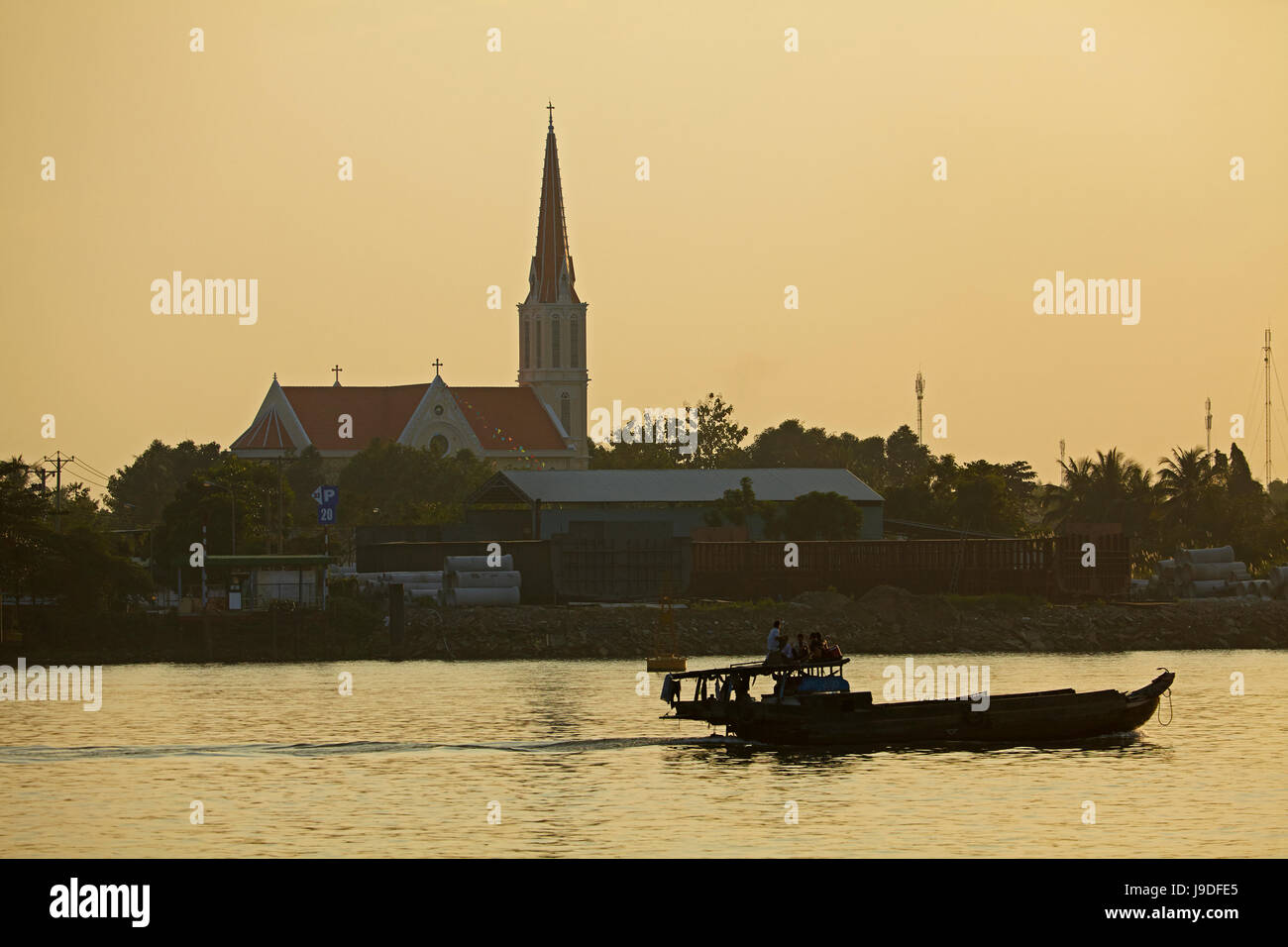Barca sul Co Chien Fiume (ramo del fiume Mekong) e silhouette di chiesa, Vinh Long, Delta del Mekong, Vietnam Foto Stock