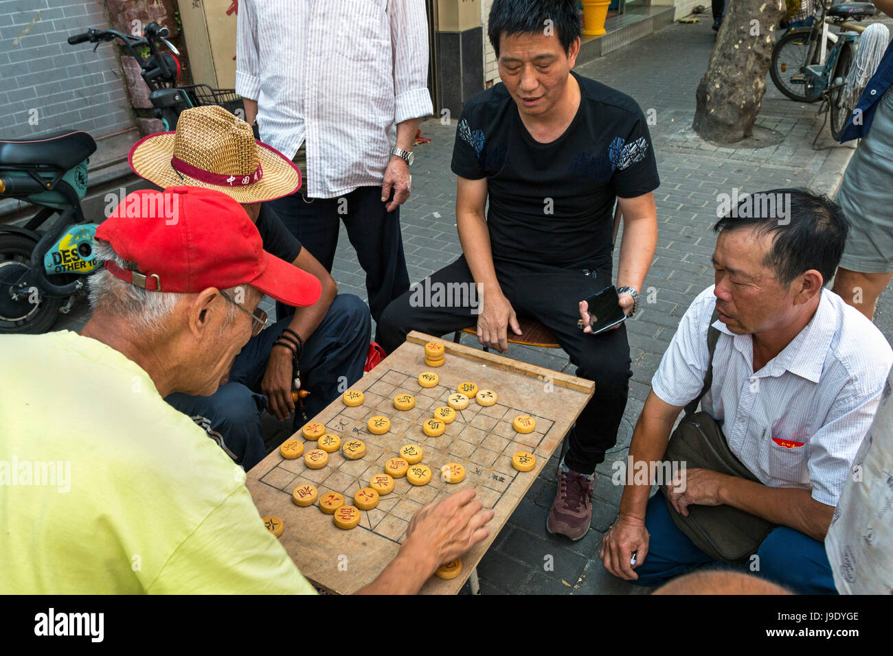 Cinese i cittadini senior giocare gioco di bordo in strada, Shanghai, Cina Foto Stock