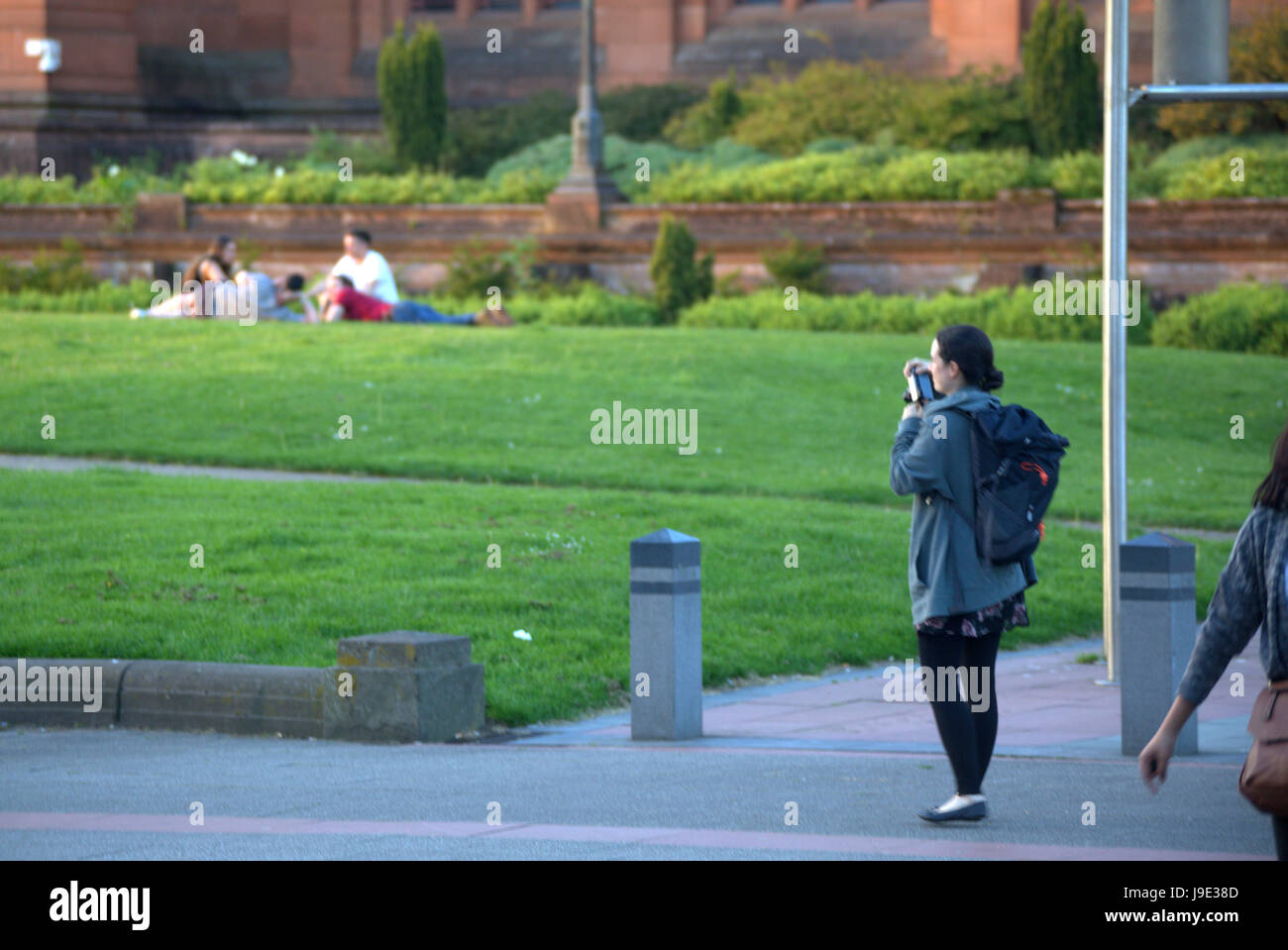 Ragazza giovane fotografa un altro gruppo di persone furtivamente sul suo telefono fotocamera Foto Stock