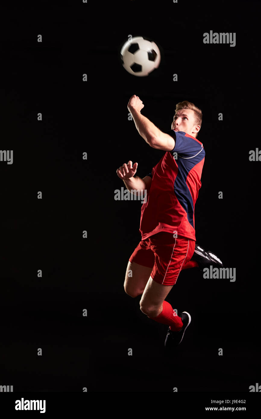 Calciatore professionista saltando alla testa palla in Studio Foto Stock Calciatore professionista saltando alla testa palla in Studio Foto Stock