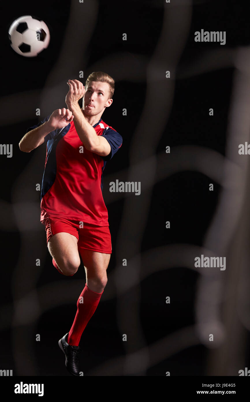 Calciatore professionista saltando alla testa palla in Studio Foto Stock Calciatore professionista saltando alla testa palla in Studio Foto Stock