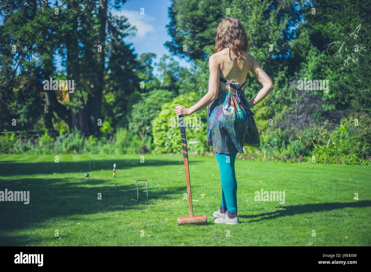 Una giovane donna è la riproduzione di croquet su un prato Foto Stock