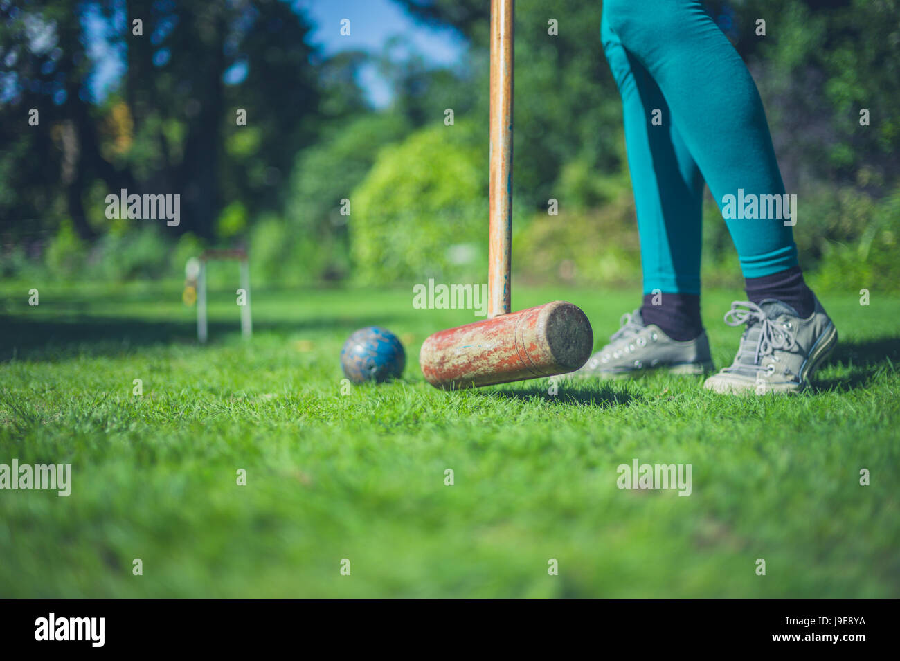 Una giovane donna è la riproduzione di croquet su un prato Foto Stock