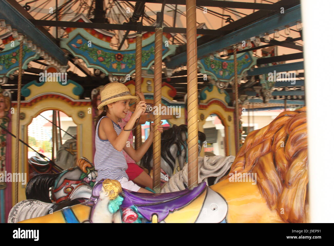 Ragazza giovane di equitazione a merry-go-round, sorridente e ripresa di un video Foto Stock