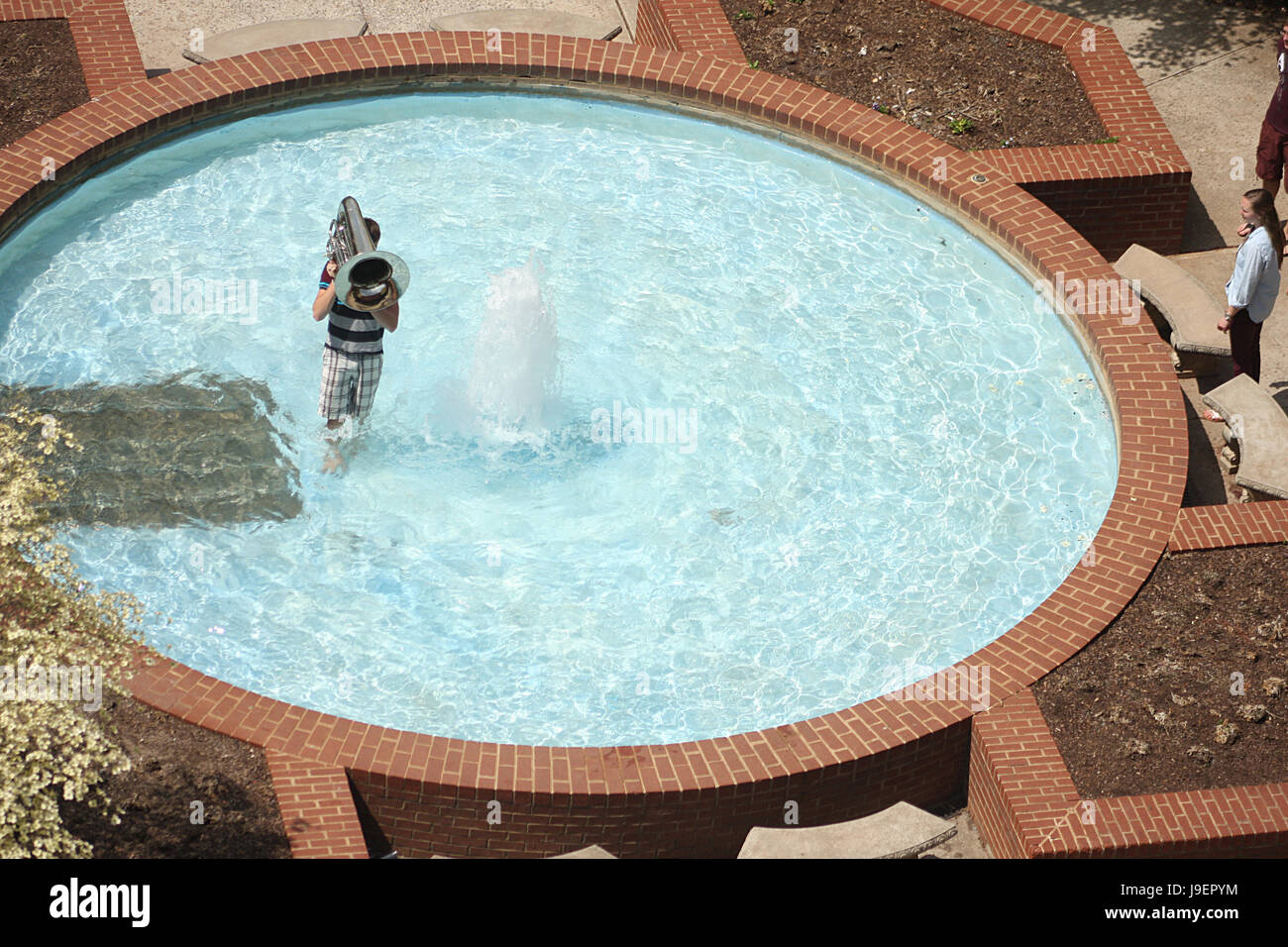 Giovane ragazzo giocando tuba nella fontana di acqua nel giorno di estate Foto Stock