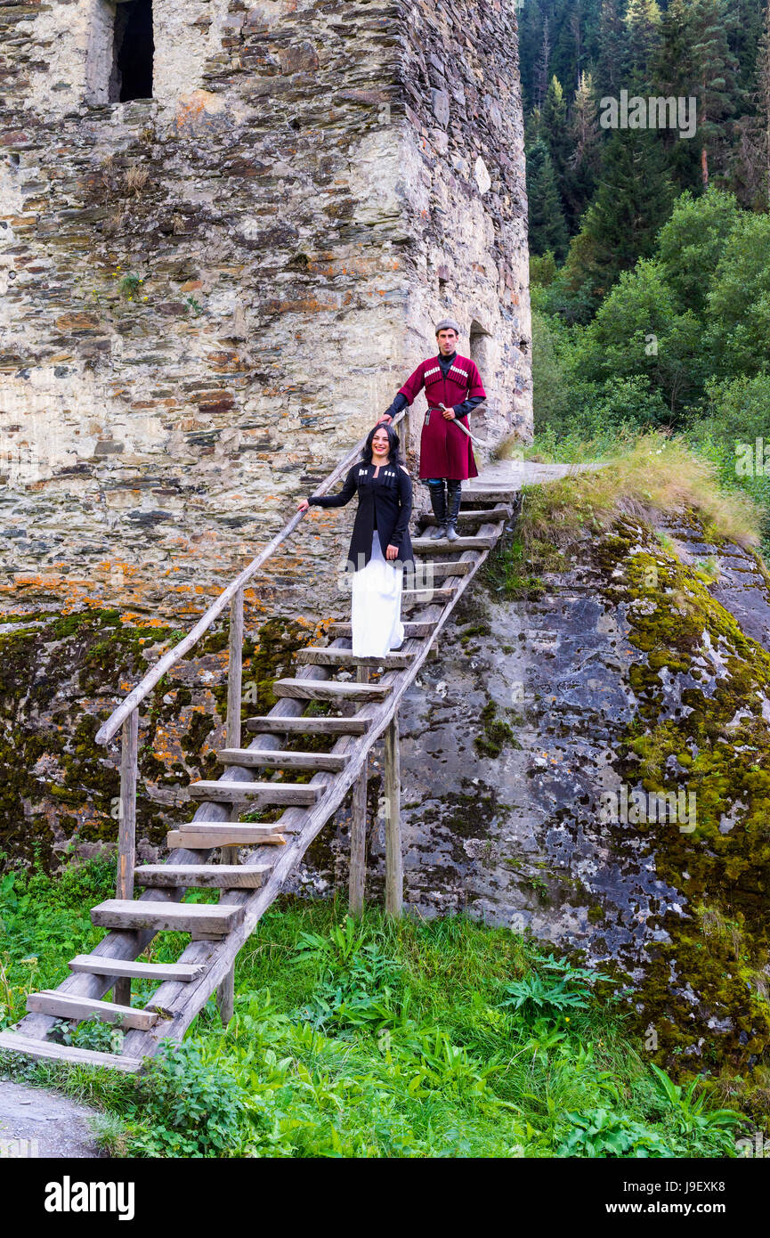 Georgian giovane in abito tradizionale scendendo le scale in legno dalla torre di amore, per il solo uso editoriale, Ushguli, regione di Svaneti, Georgia Foto Stock