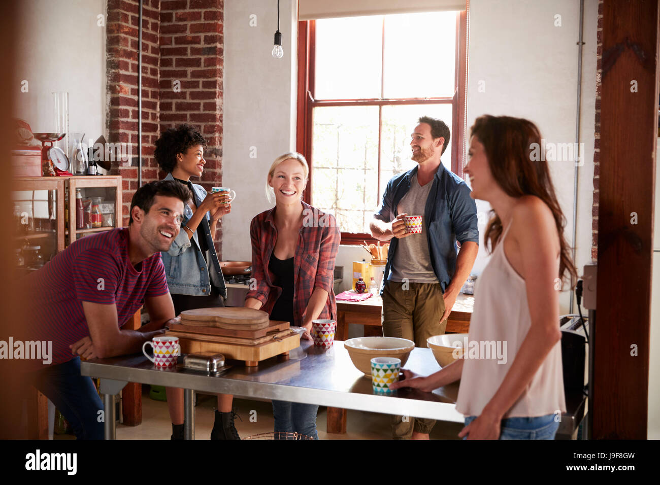 Cinque amici di ridere davanti a un caffè in cucina, close up Foto Stock