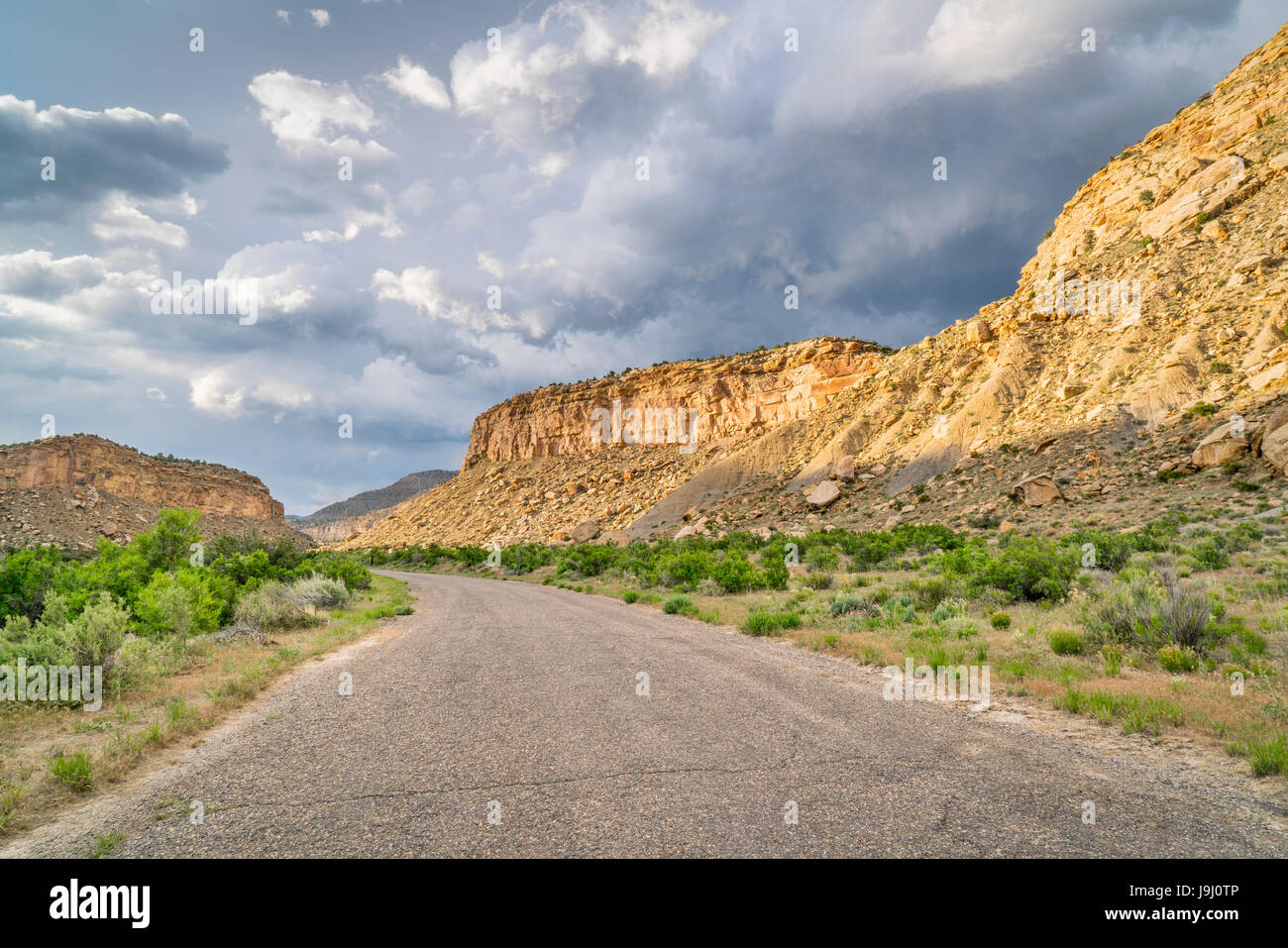 Thompson Canyon road attraverso Prenota Cliffs in Eastern Utah con pesanti nuvole di tempesta Foto Stock