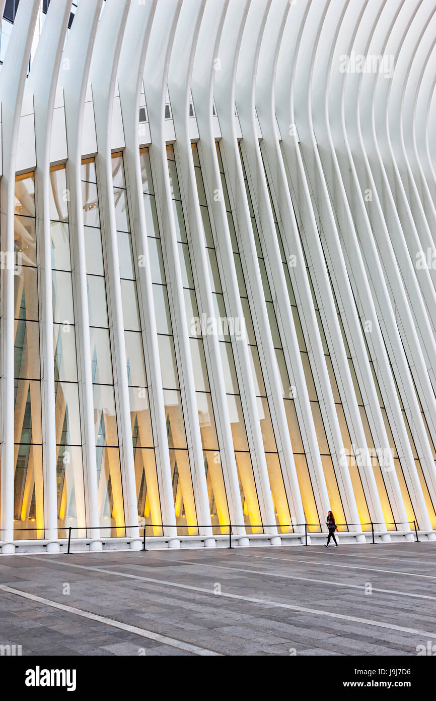 Donna che cammina accanto al World Trade Center Hub di trasporto da Santiago Calatrava esterno, New York Cit. Foto Stock