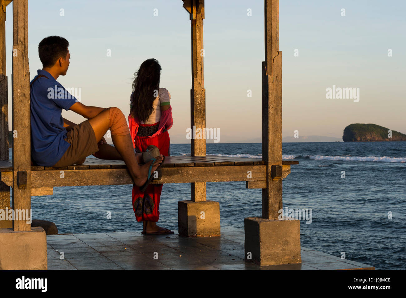 Coppia giovane dal mare di fronte Candi Dasa con Gili Mimpang e Gili Tepekong Foto Stock