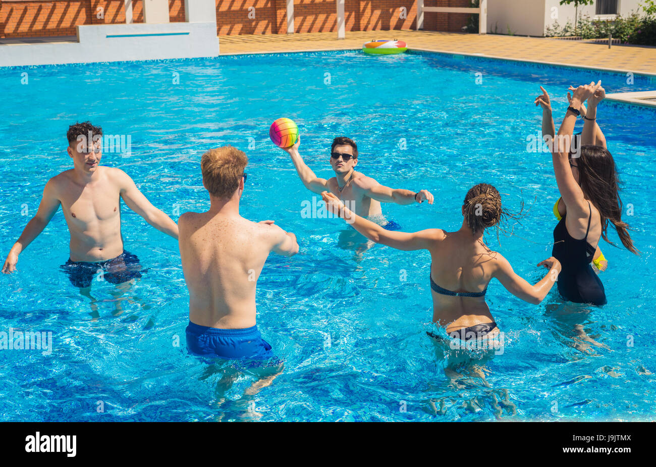 Il gruppo di allegro coppie amici giocare pallavolo in acqua Foto Stock