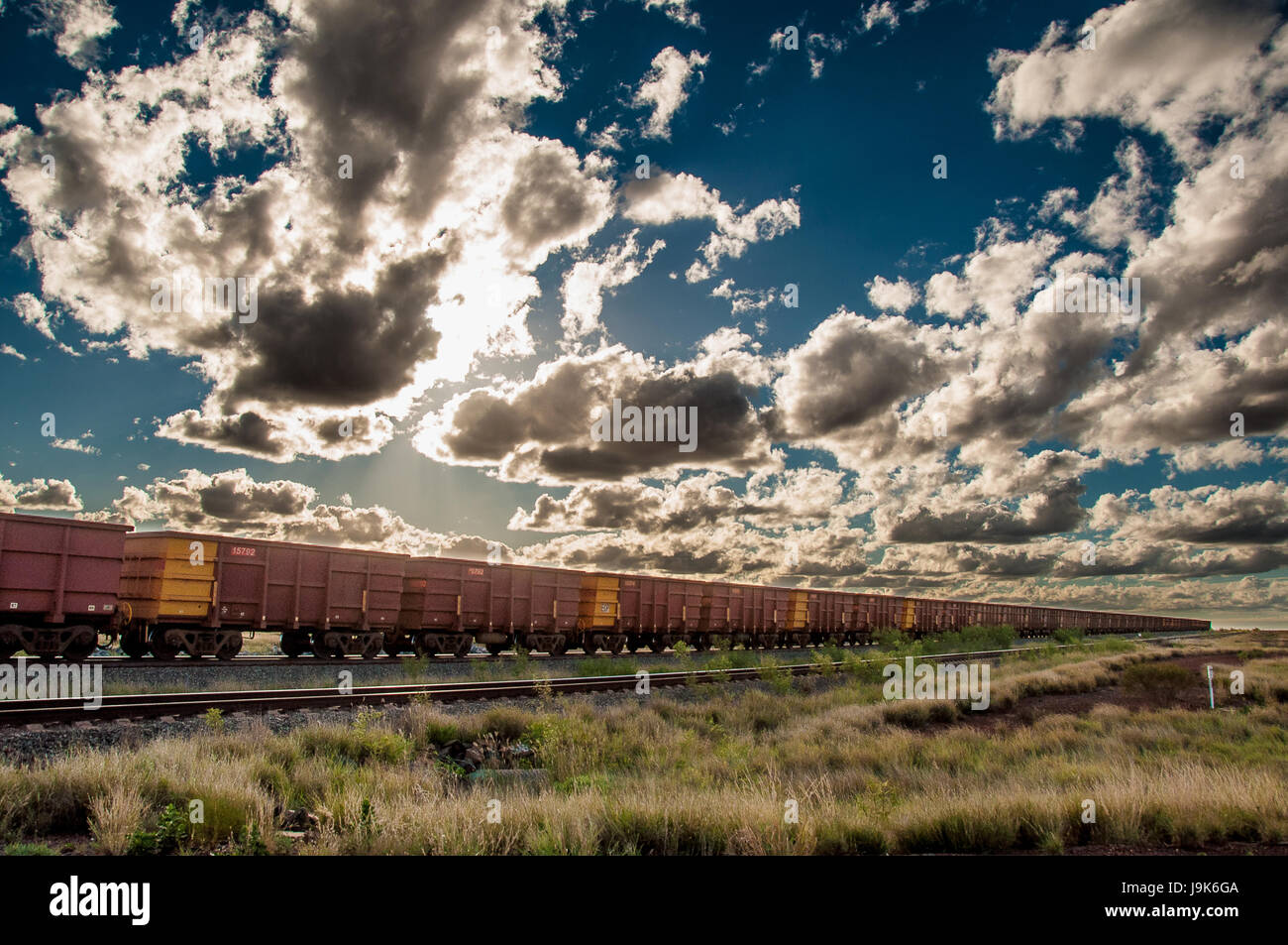 Un minerale di ferro treno sotto un cielo drammatico nella regione Pilbara dell Australia Occidentale. Foto Stock