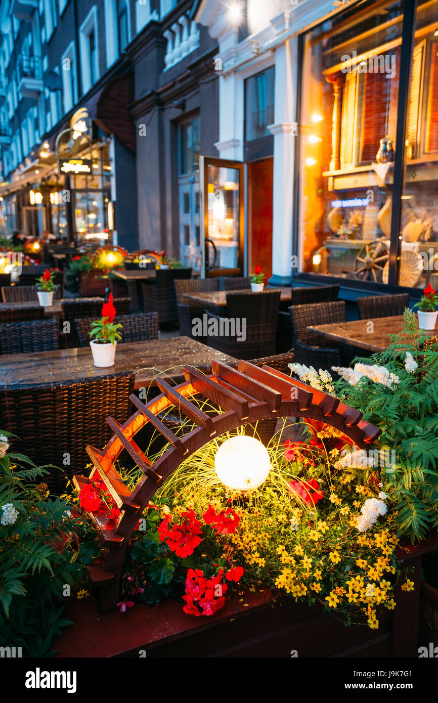 Illuminazione decorativa vicino a tavoli liberi di una Street Cafe la sera o la notte illuminazione nella vecchia città europea. Foto Stock