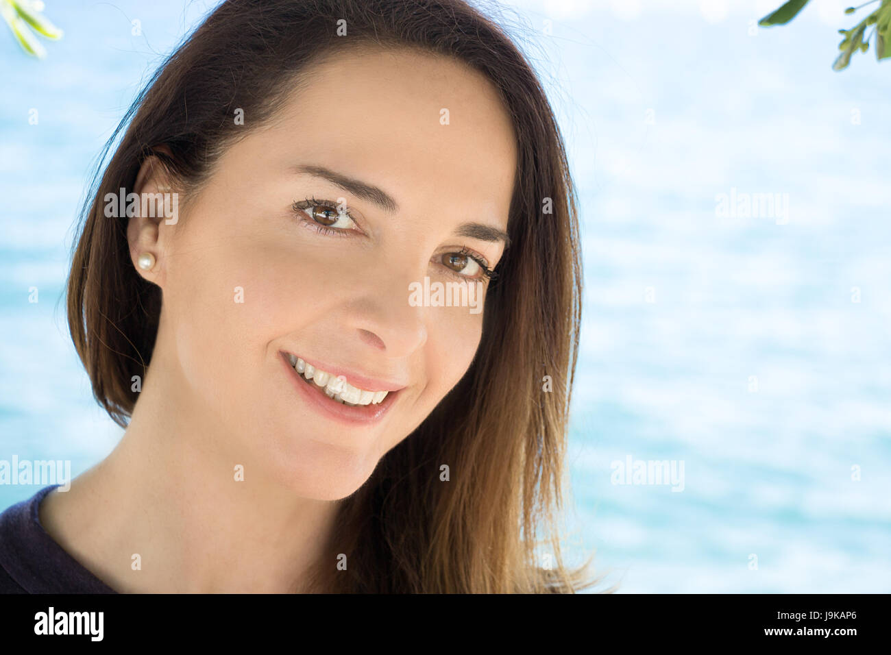 Ritratto di una donna di 45 anni, guardando la telecamera, sorridente, spiaggia sfondo, all'esterno. Foto Stock