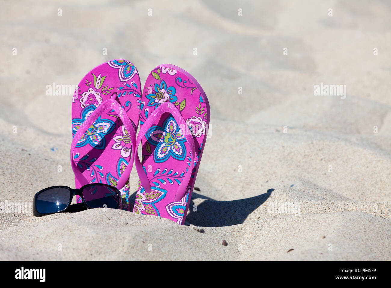 Flip-flop e occhiali da sole sulla spiaggia Foto Stock