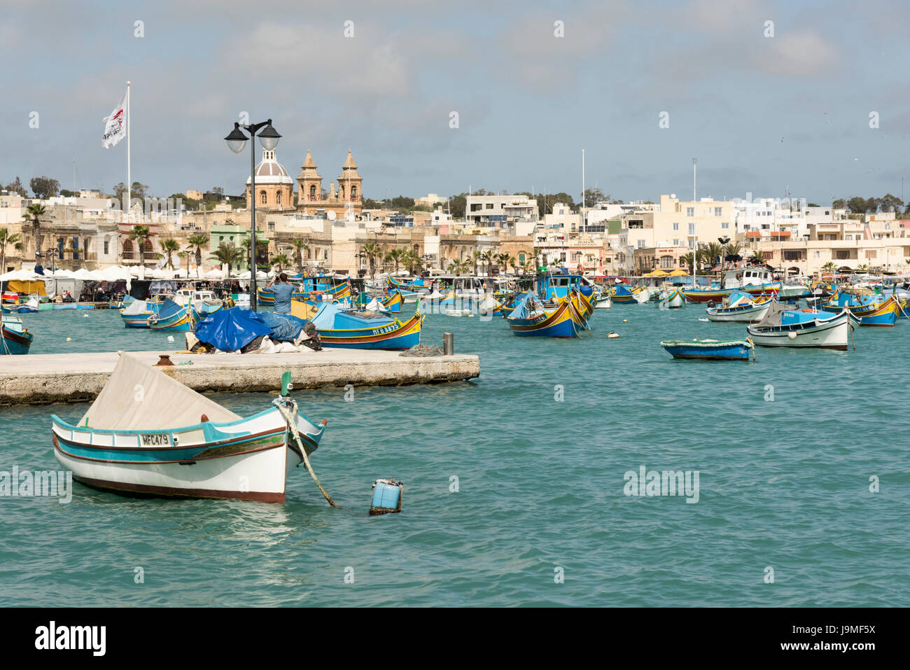 Tradizionale Maltese barche da pesca o luzzu, dipinto luminosamente nel porto di Marsaxlokk a Malta Foto Stock