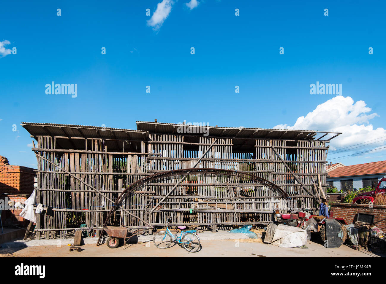 Cortile vicino Xifeng, Liaoning, Cina. La grande struttura in legno è utilizzata per l'asciugatura e la memorizzazione di pannocchie di granoturco che sono un fiocco in questa zona. Foto Stock