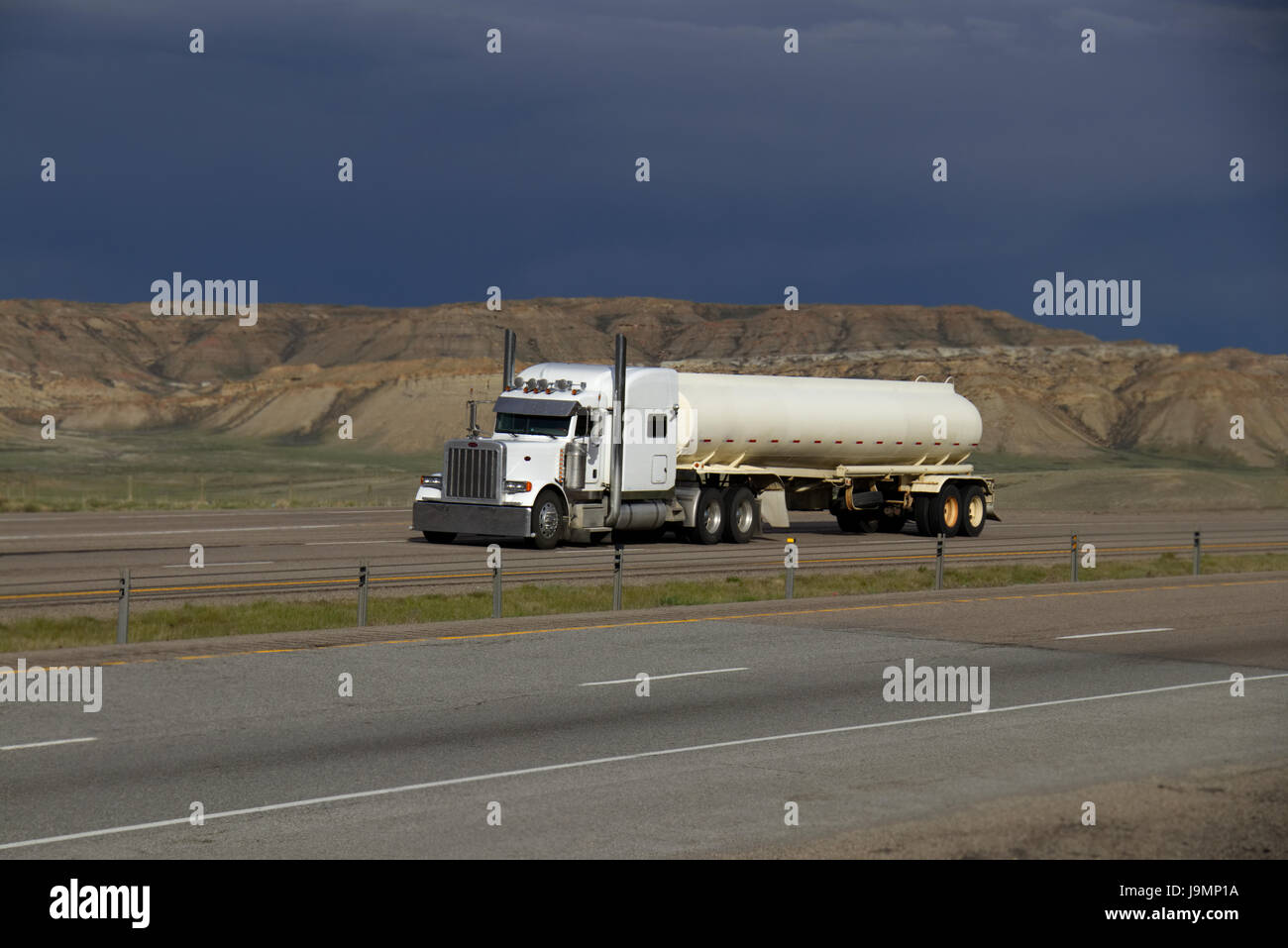 Classic Semi-Truck tirando White cisterna rimorchio verso il basso un rurale noi Interstate. Tutti i contrassegni rimossi. Foto Stock