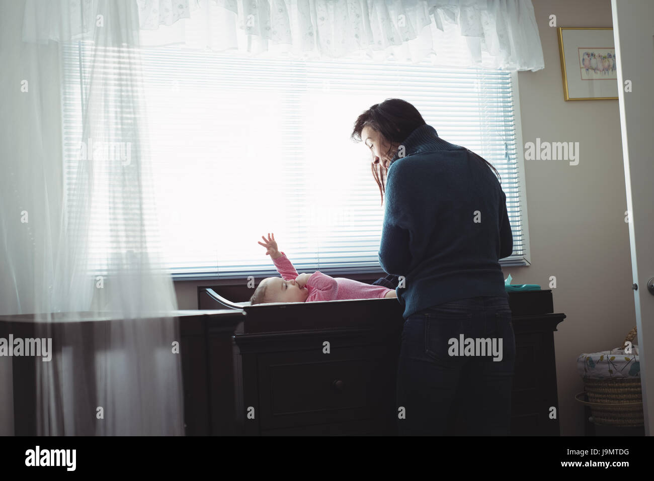 Madre cambiando pannolino della sua bambina nella stanza del bambino a casa Foto Stock