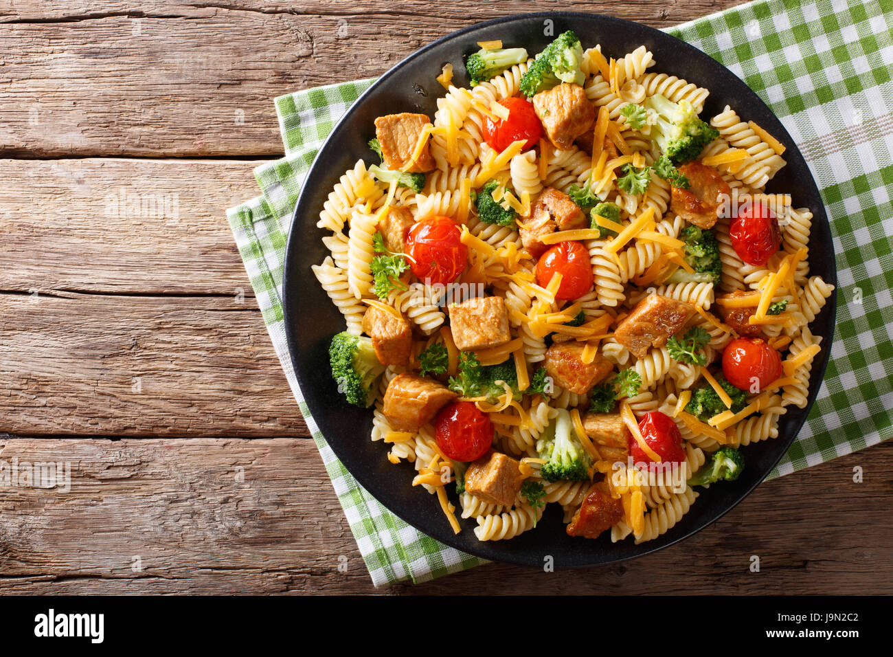 Fusilli con carne di maiale, broccoli, i pomodori e il formaggio cheddar vicino sul tavolo. vista orizzontale dal di sopra Foto Stock