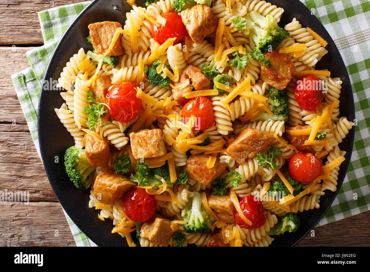 Pasta fusilli con carne di maiale, broccoli, i pomodori e il formaggio cheddar macro su una piastra orizzontale di vista da sopra Foto Stock