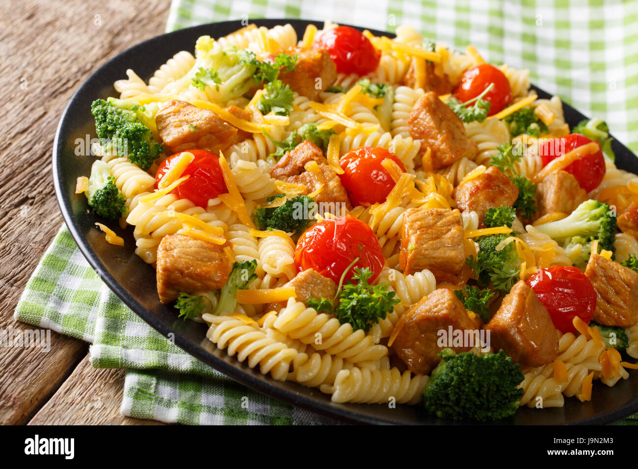 Deliziosi fusilli con carne di maiale tritata, broccoli, i pomodori e il cheddar closeup su una piastra orizzontale. Foto Stock
