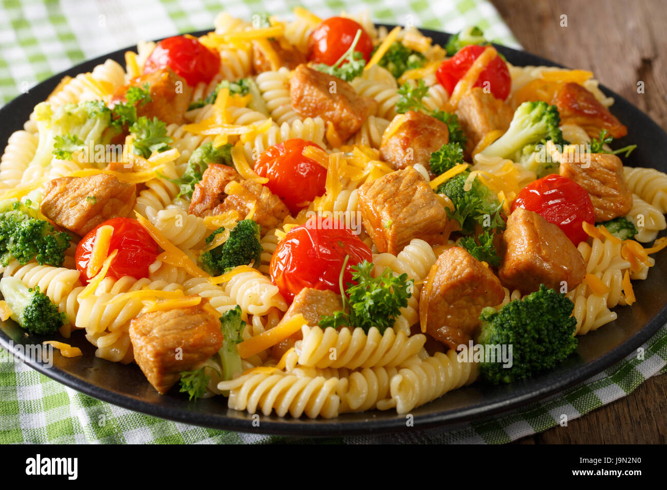 Fusilli fatti in casa La pasta italiana con maiale fritto, broccoli, i pomodori e il cheddar close-up su una piastra orizzontale. Foto Stock