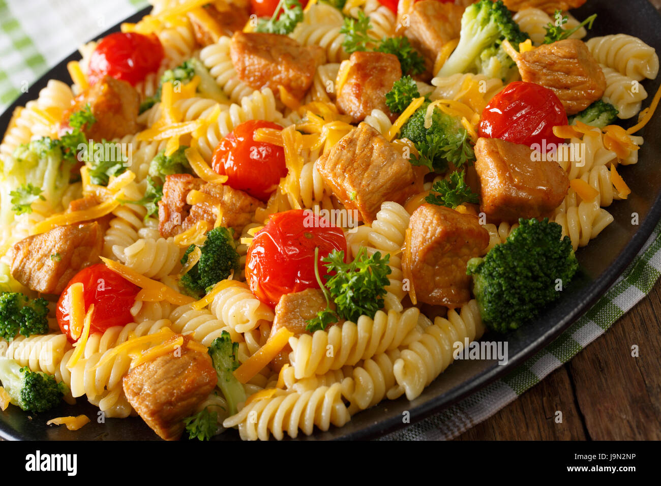 Insalata tiepida di fusilli con carne di maiale, broccoli e pomodori close-up su una piastra orizzontale. Foto Stock