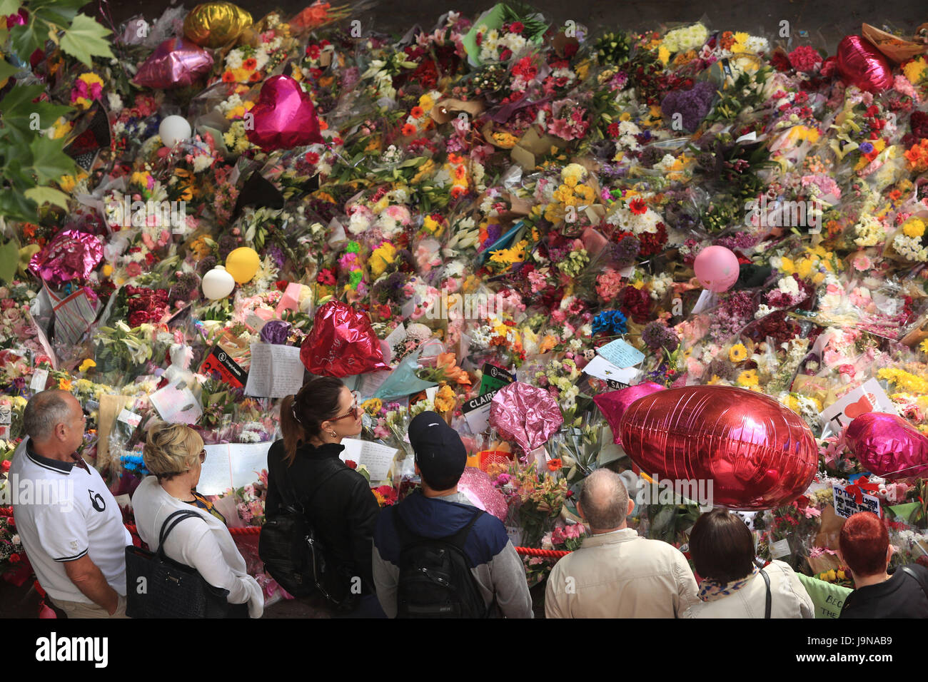 La gente guarda i fiori e omaggi a sinistra in St Ann's Square a Manchester in seguito alla Manchester Arena attacco terroristico. Foto Stock