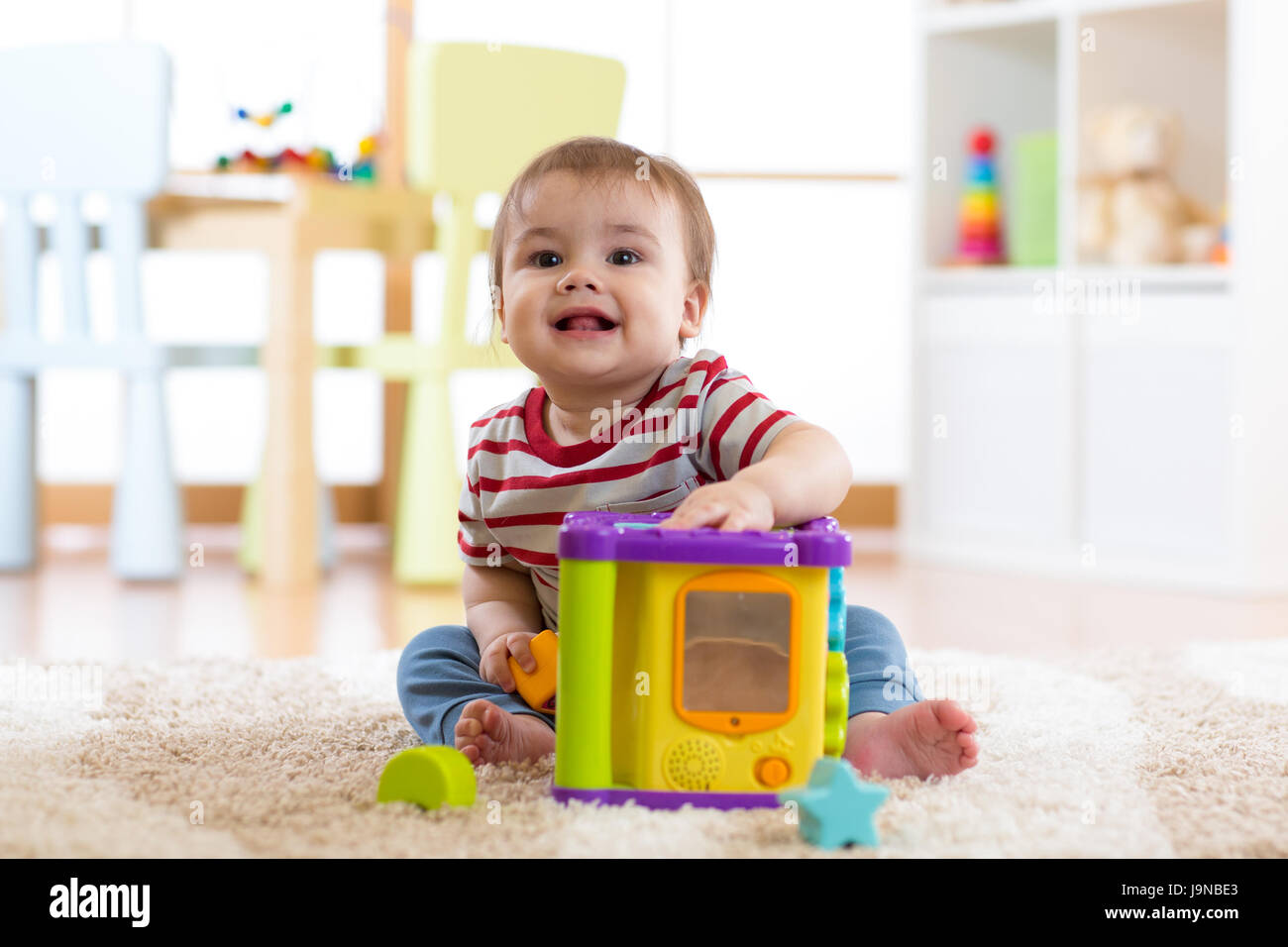 Il toddler boy giocando in interni con selezionatrice giocattolo seduto sul tappeto morbido Foto Stock