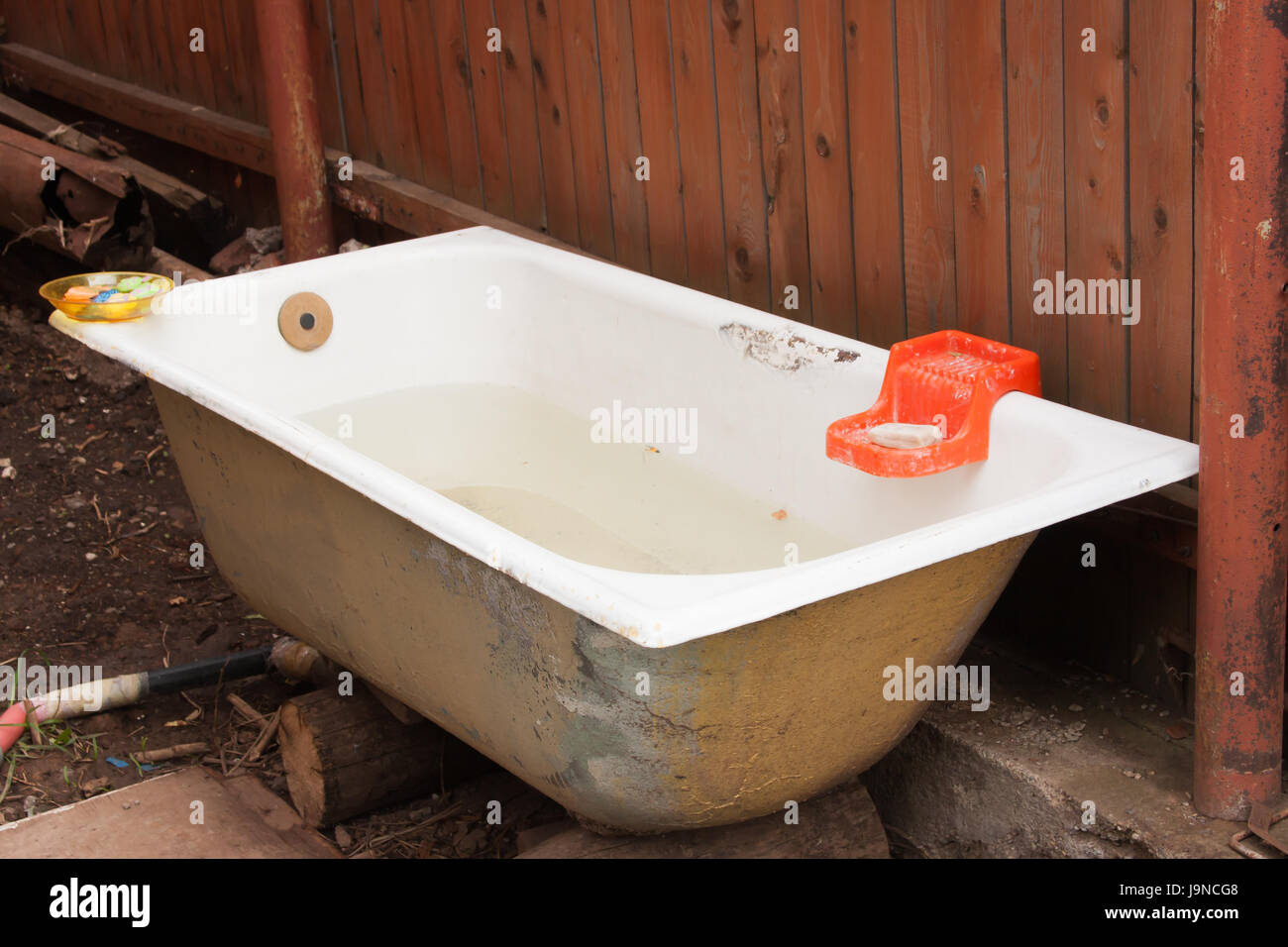 Vecchio ghisa vasca da bagno sorge in un orto nei pressi di una recinzione Foto Stock