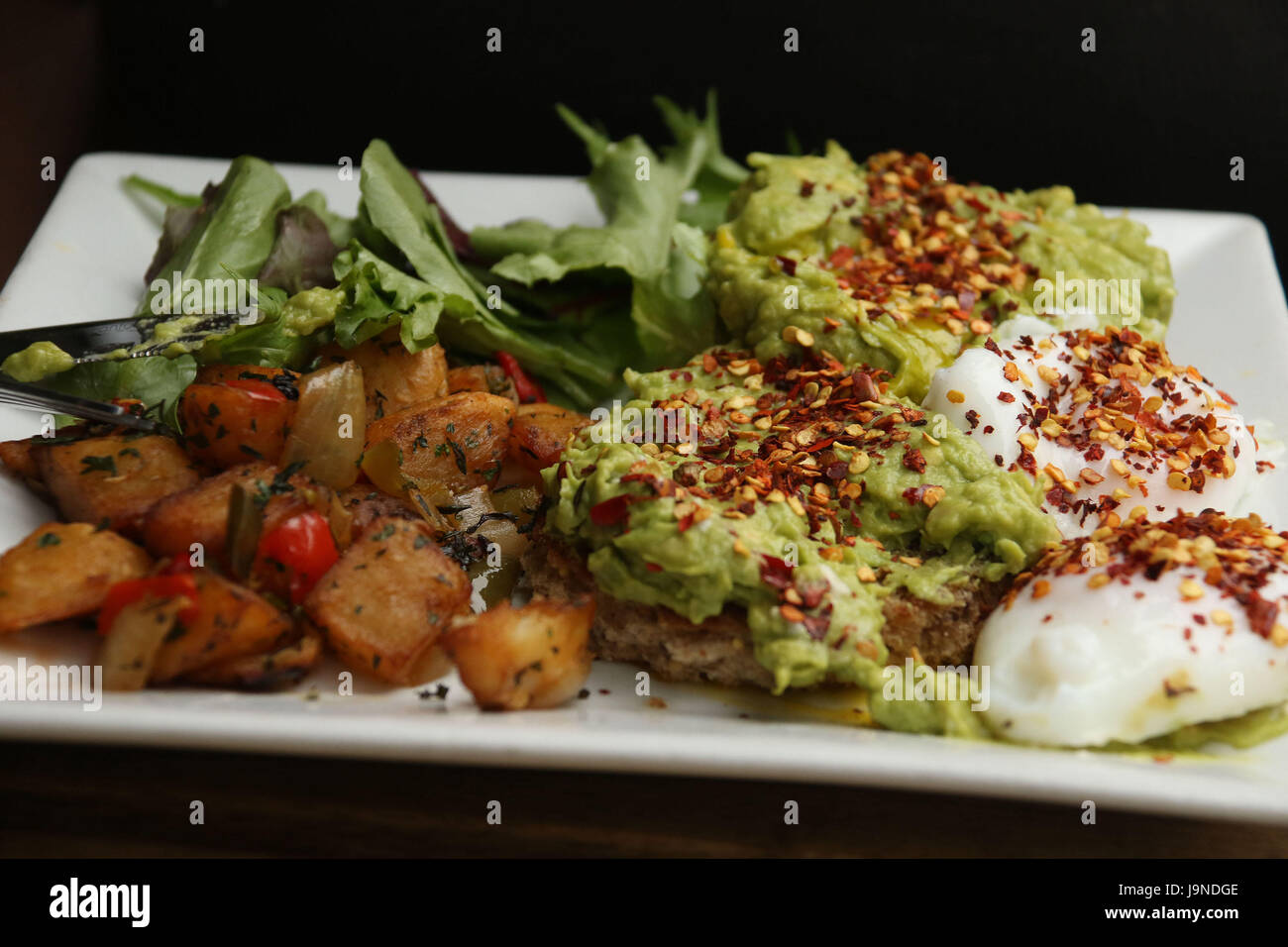 Uova al tegame con diffusione di avocado con peperoncino semi Foto Stock