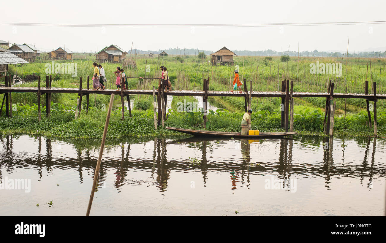 La gente camminare lungo un dock nel Lago Inle, Myanmar. Foto Stock