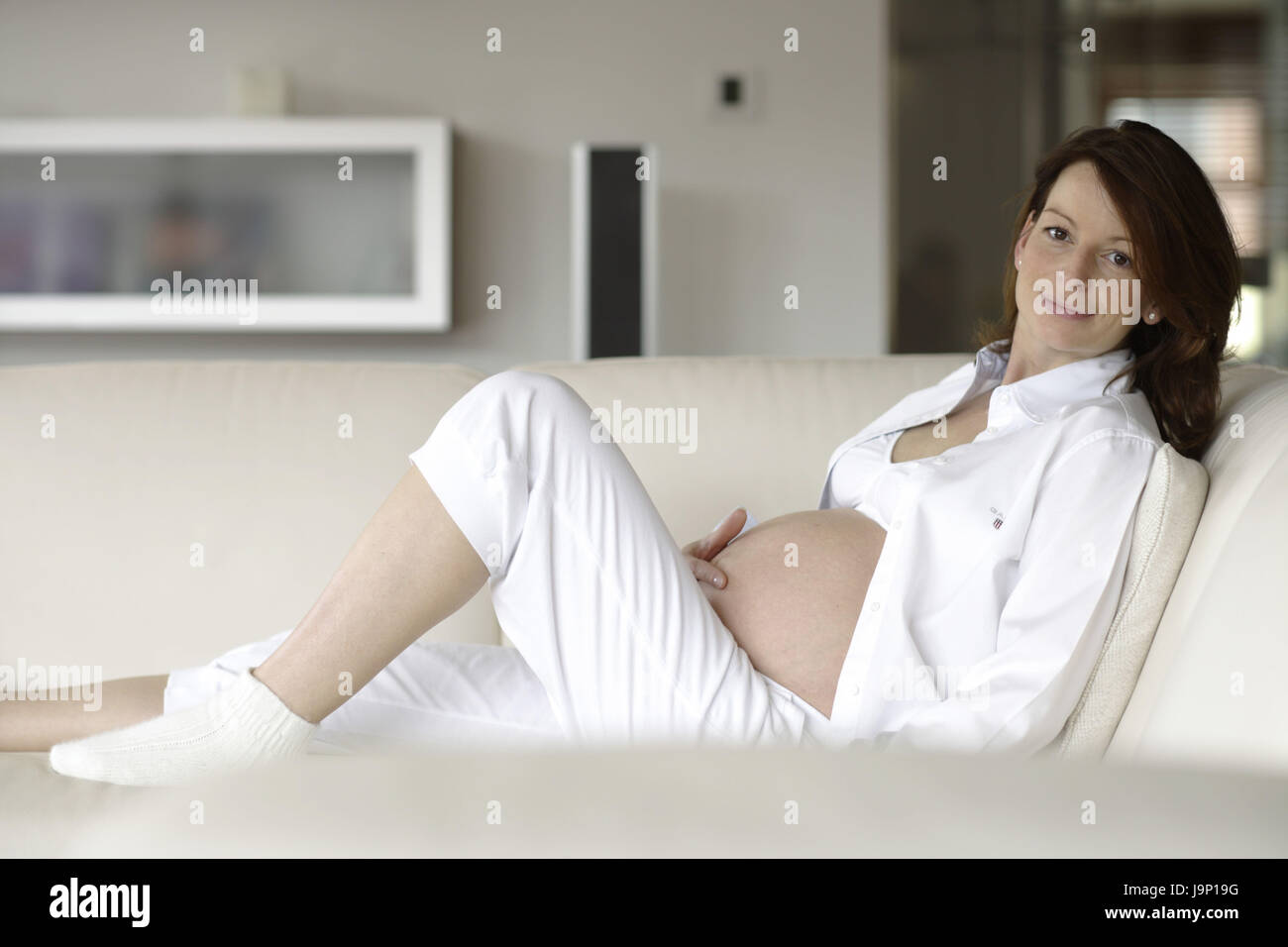 Donna,si trovano in stato di gravidanza,camicetta apertamente,divano,mano,baby addome,touch, Foto Stock
