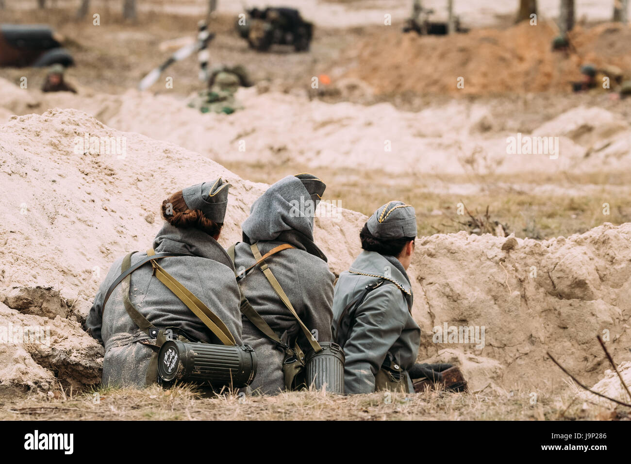 Le donne non identificato Re-enactors vestito come Wehrmacht tedesca Radio militare gli operatori nella II Guerra Mondiale seduta nascosti in trincea In autunno Battlefield Dur Foto Stock