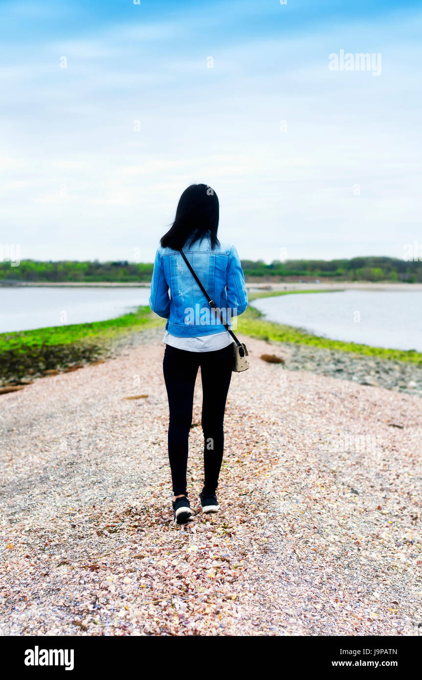 Una donna cinese a piedi su un sandbar a lowtide da Charles isola di silver sands state park in Milford Connecticut. Foto Stock