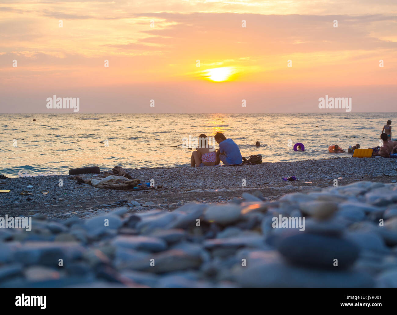 Un giovane e ripiegati a piramide Zen pietre ghiaia sul mare spiaggia al tramonto Foto Stock